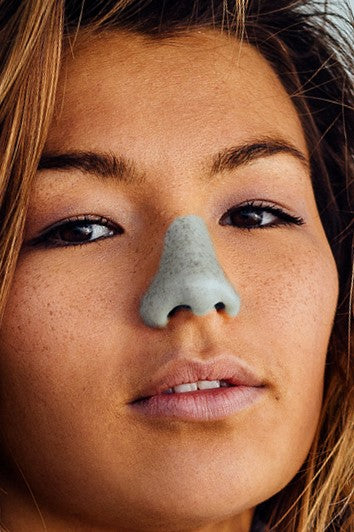 Closeup of woman with green Noz sunscreen on nose