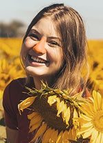 Load image into Gallery viewer, Girl in sunflower field with orange Noz sunscreen on nose
