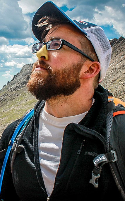 Man outdoors wearing yellow Noz sunscreen on nose